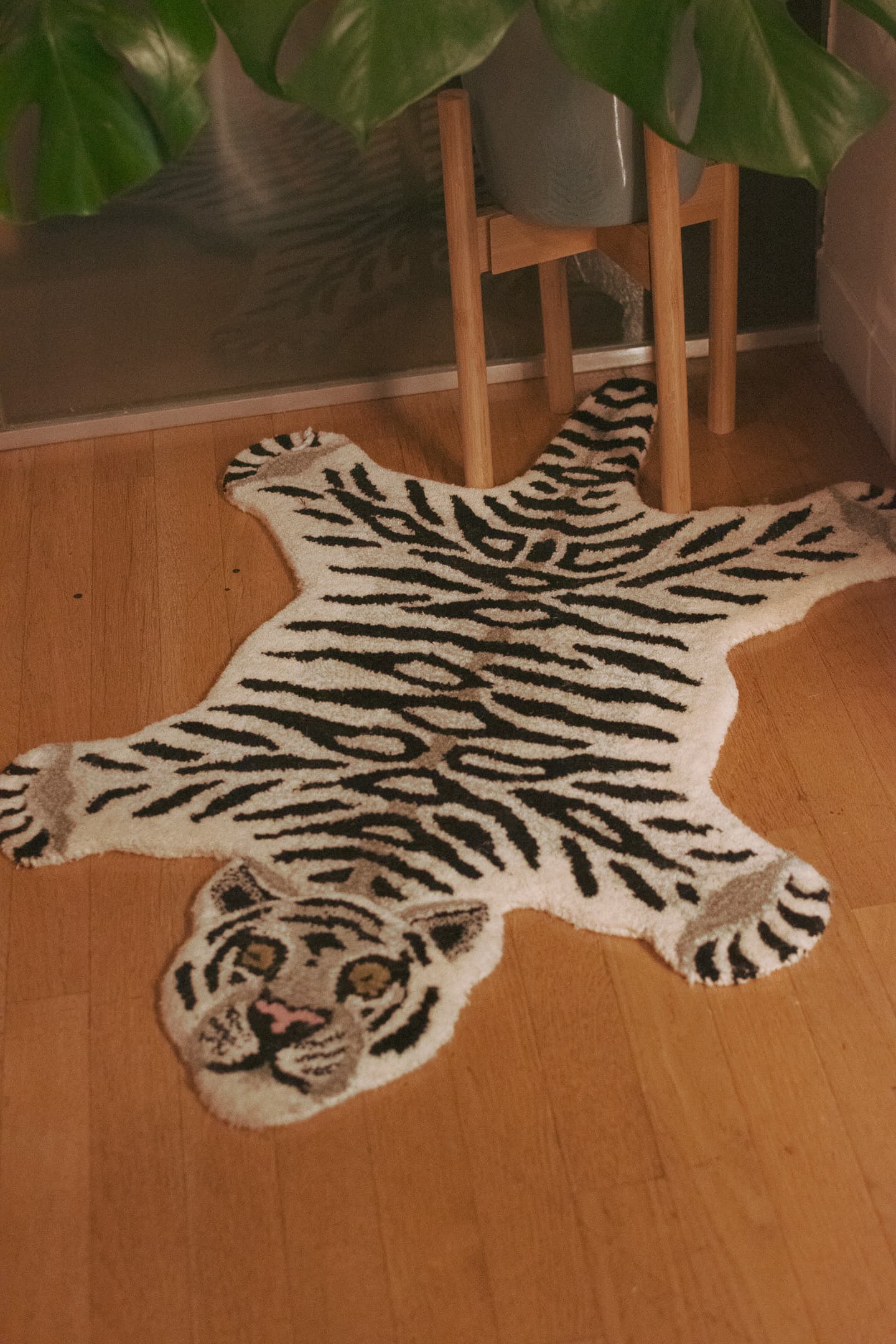 A tiger-print rug on a wooden floor with a plant in the background