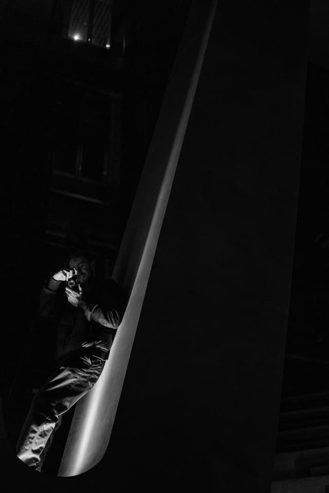 A black and white photo capturing a person on a slide, partially obscured by shadows