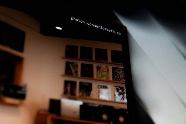 A blurred interior scene with a shelf holding various items, including books or records, under a dark ceiling with visible text