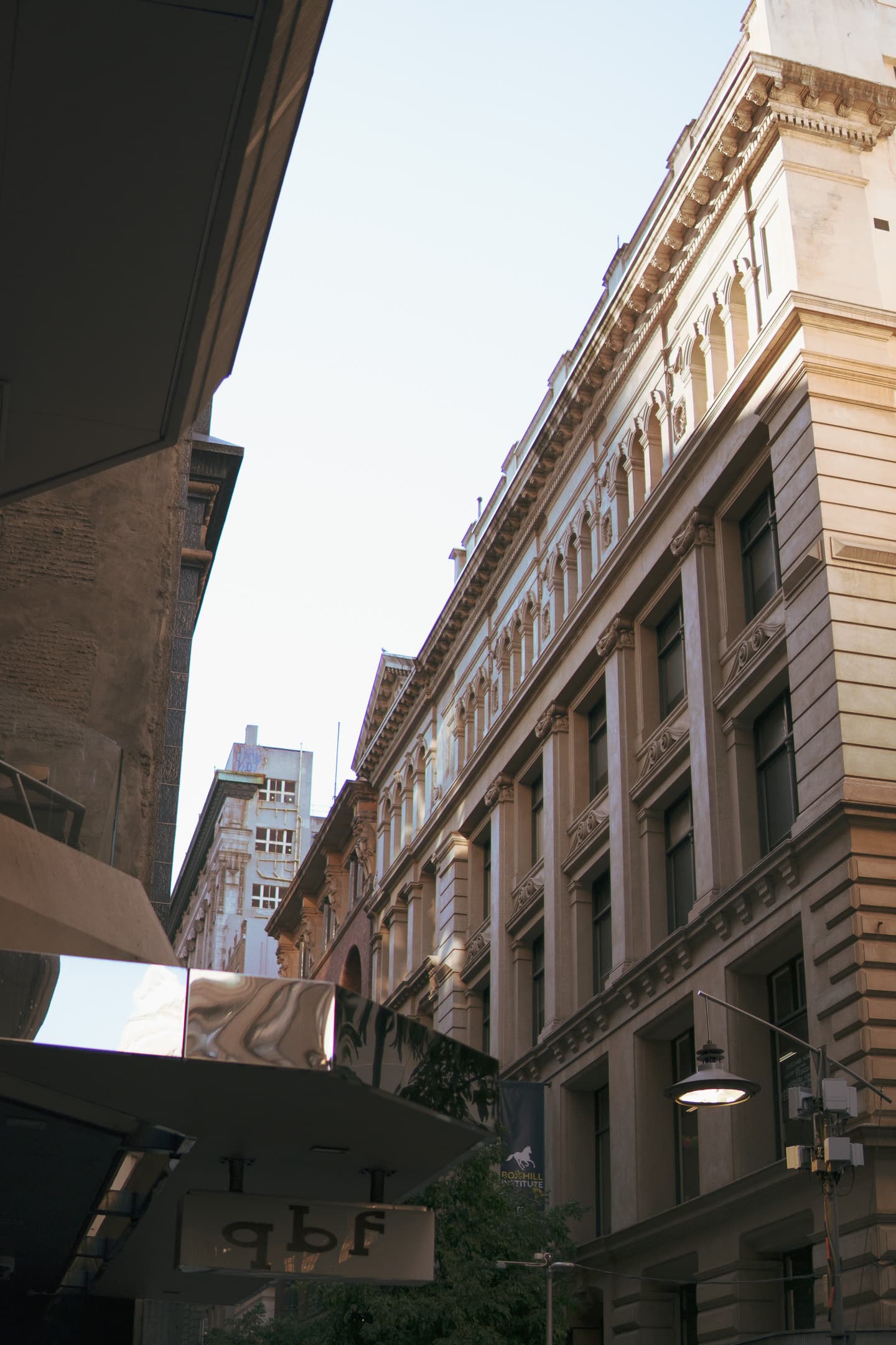 A narrow urban alleyway flanked by tall buildings with classical architecture under a clear sky