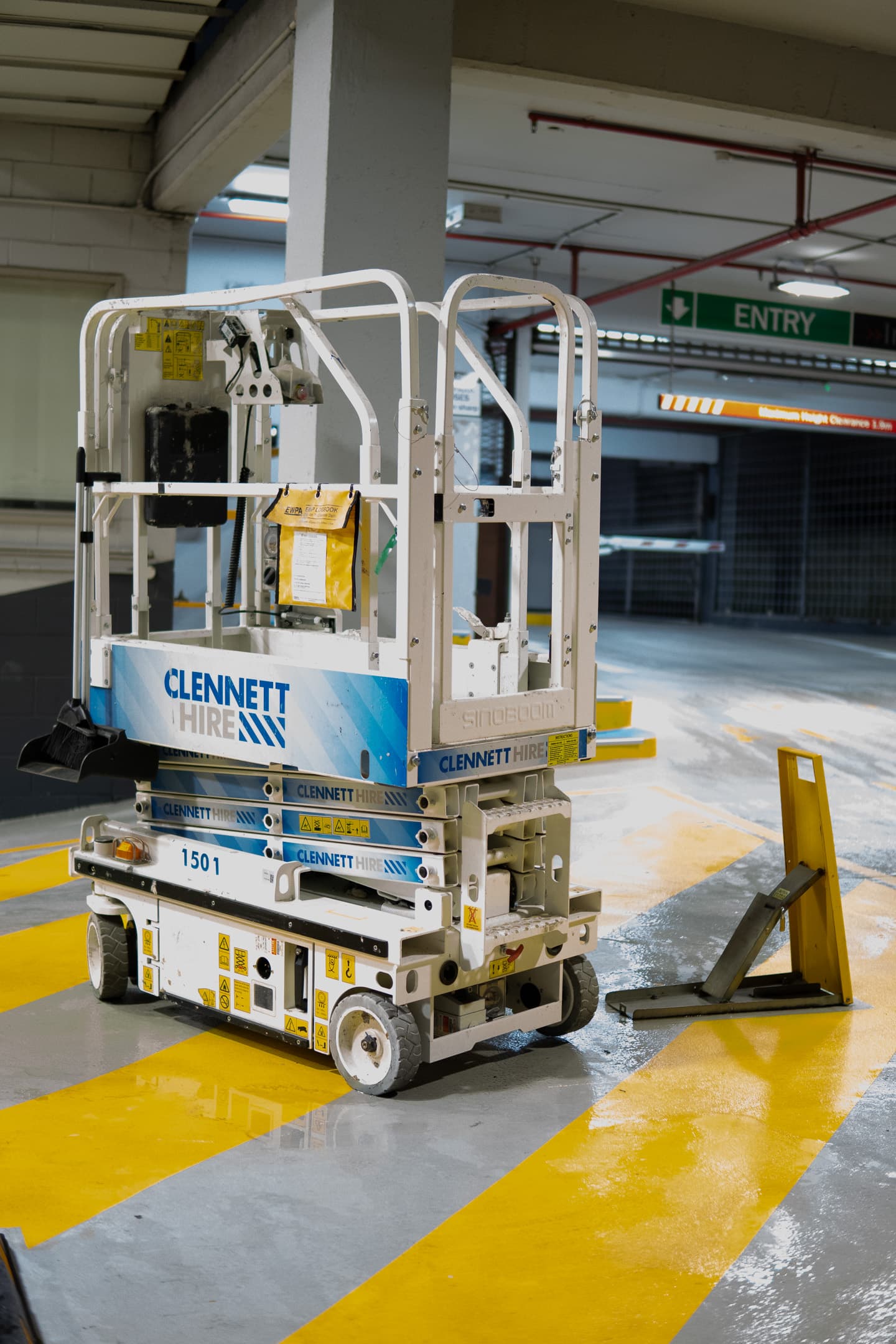 A scissor lift parked in an indoor parking area with yellow safety markings on the floor